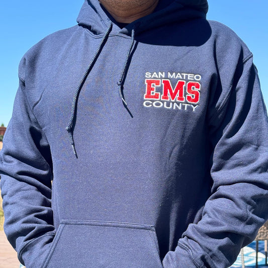 Person wearing a blue hoodie with 'San Mateo EMS County' text outdoors.