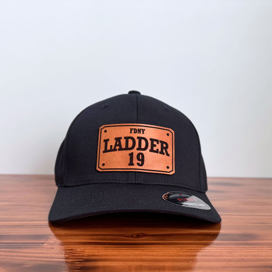 Black cap with FDNY Ladder 19 leather patch on a wooden surface