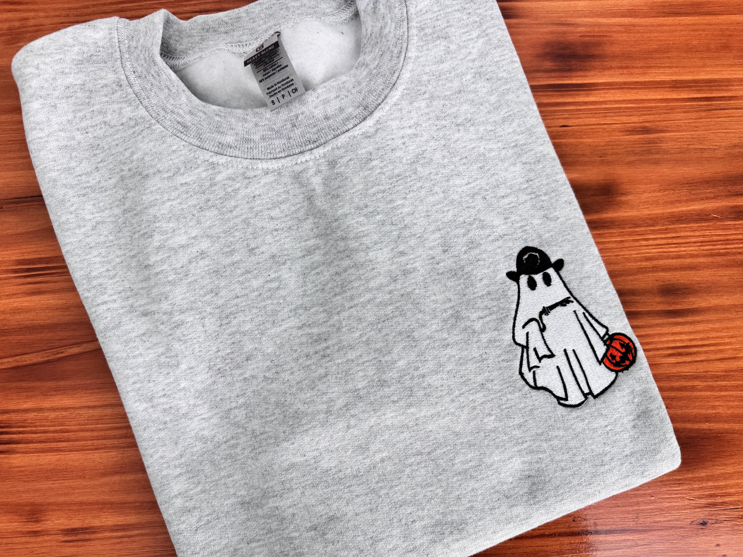 Folded gray sweatshirt with a ghost graphic on a wooden surface