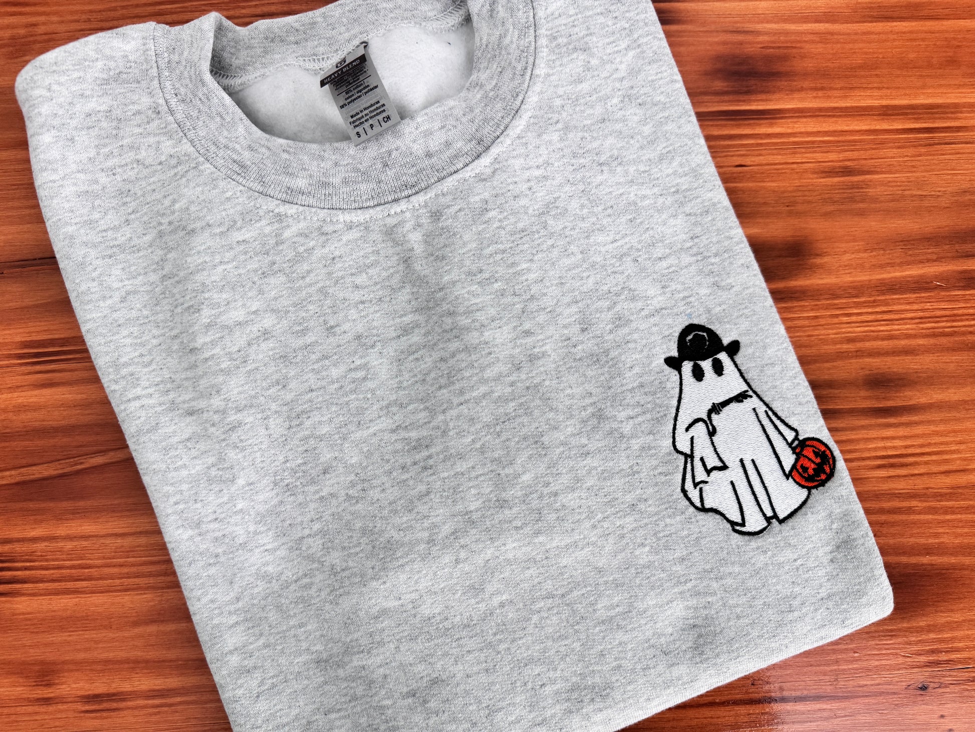 Folded gray sweatshirt with a ghost graphic on a wooden surface