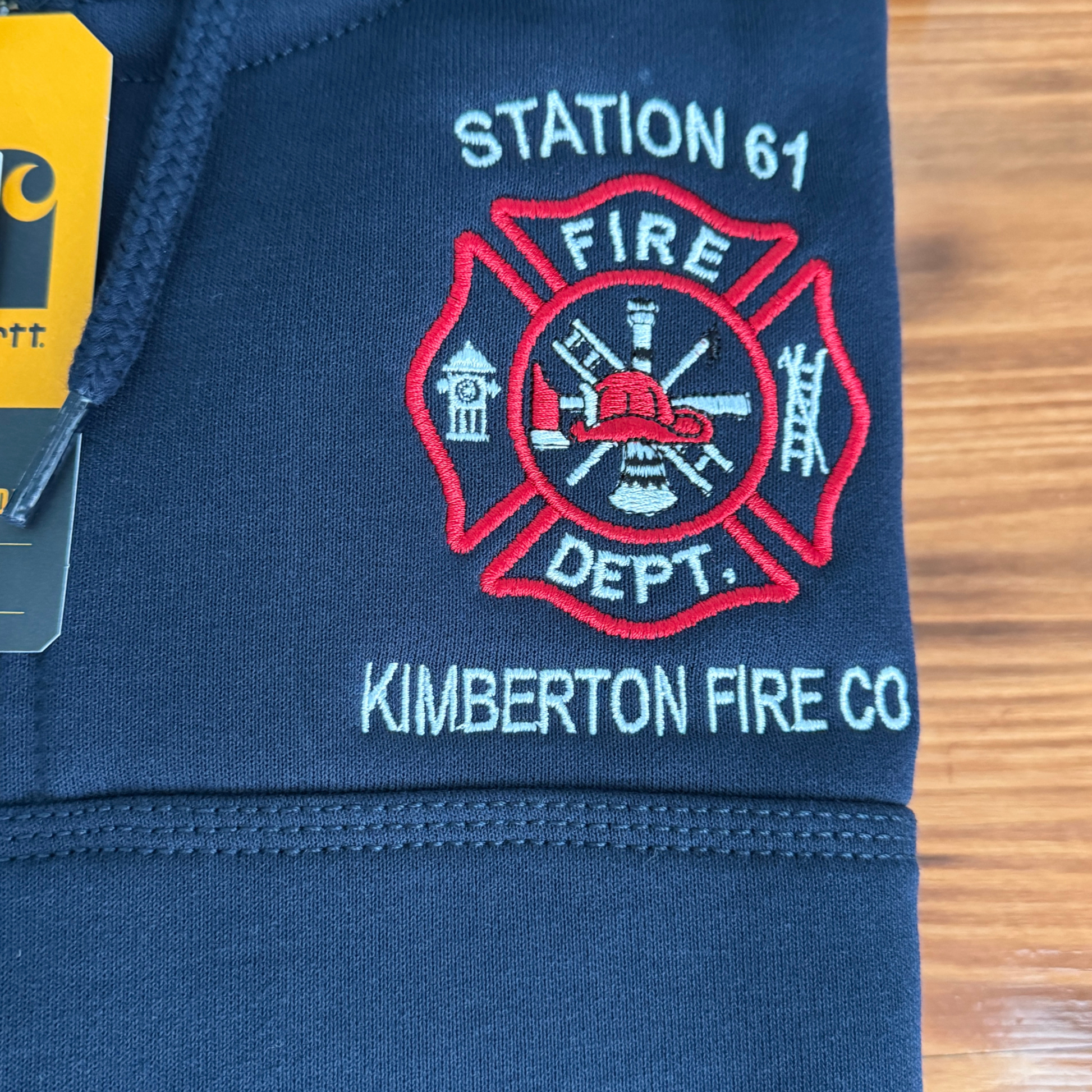 Navy blue sweatshirt with fire department logo and text on a wooden surface
